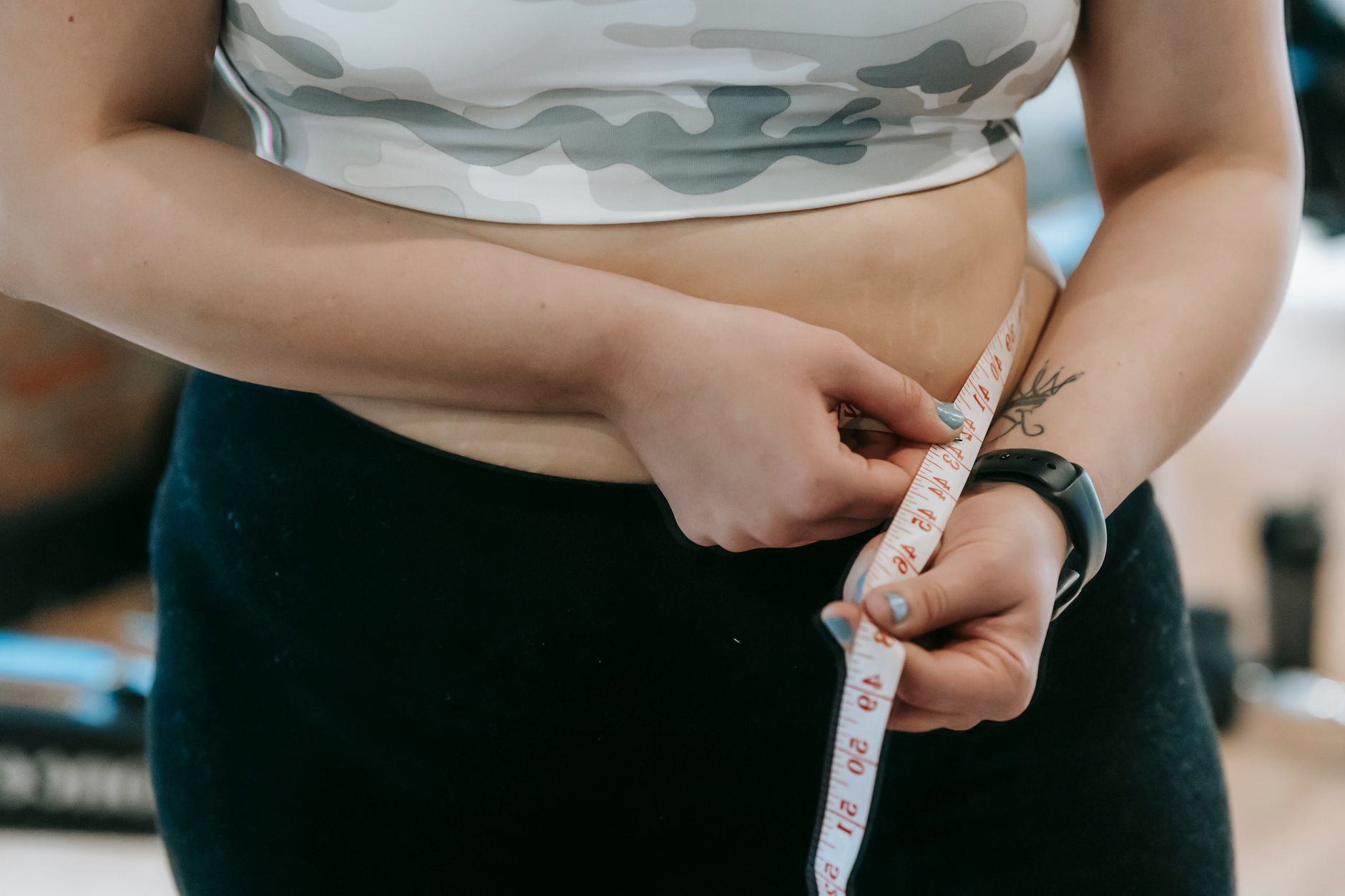 Crop anonymous plus size female with measuring tape measuring waist on blurred background — 4 Reasons Why You May Not Qualify
