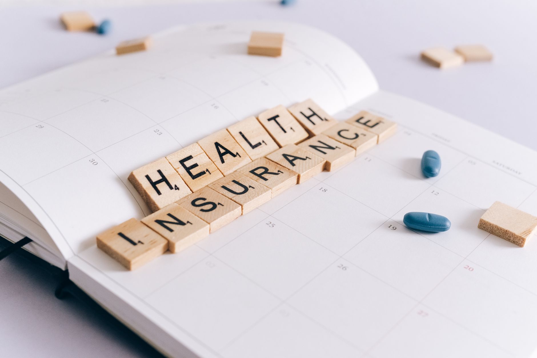 Scrabble tiles spelling 'Health Insurance' on a calendar with pills. — 5 Most Special Ways to Celebrate Thanksgiving Cocktail