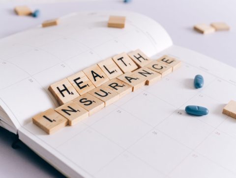 Scrabble tiles spelling 'Health Insurance' on a calendar with pills. — Athem Blue Mix Offering Two New Medical Health Insuran