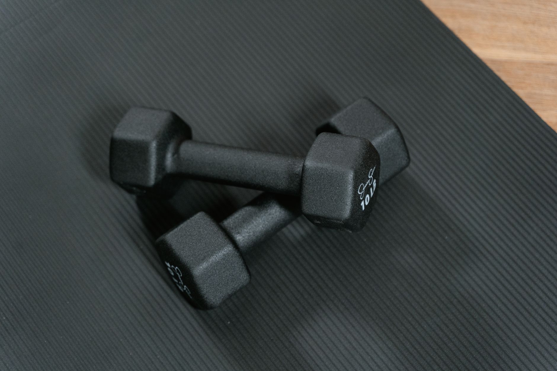 Black dumbbells placed on a yoga mat, perfect for home workouts and strength training. — Benefits of using natural cosmetics