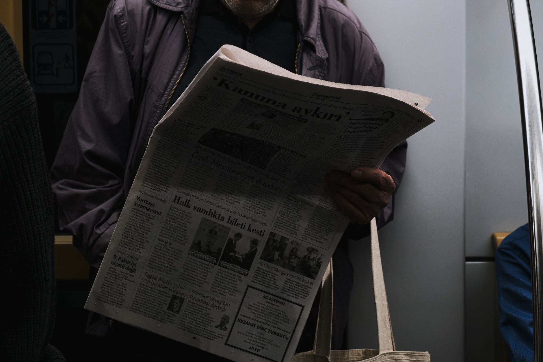 A man reads a newspaper in a dimly lit public transport setting, reflecting city life. — CBD For Anxiety - Anxiolytic Effects