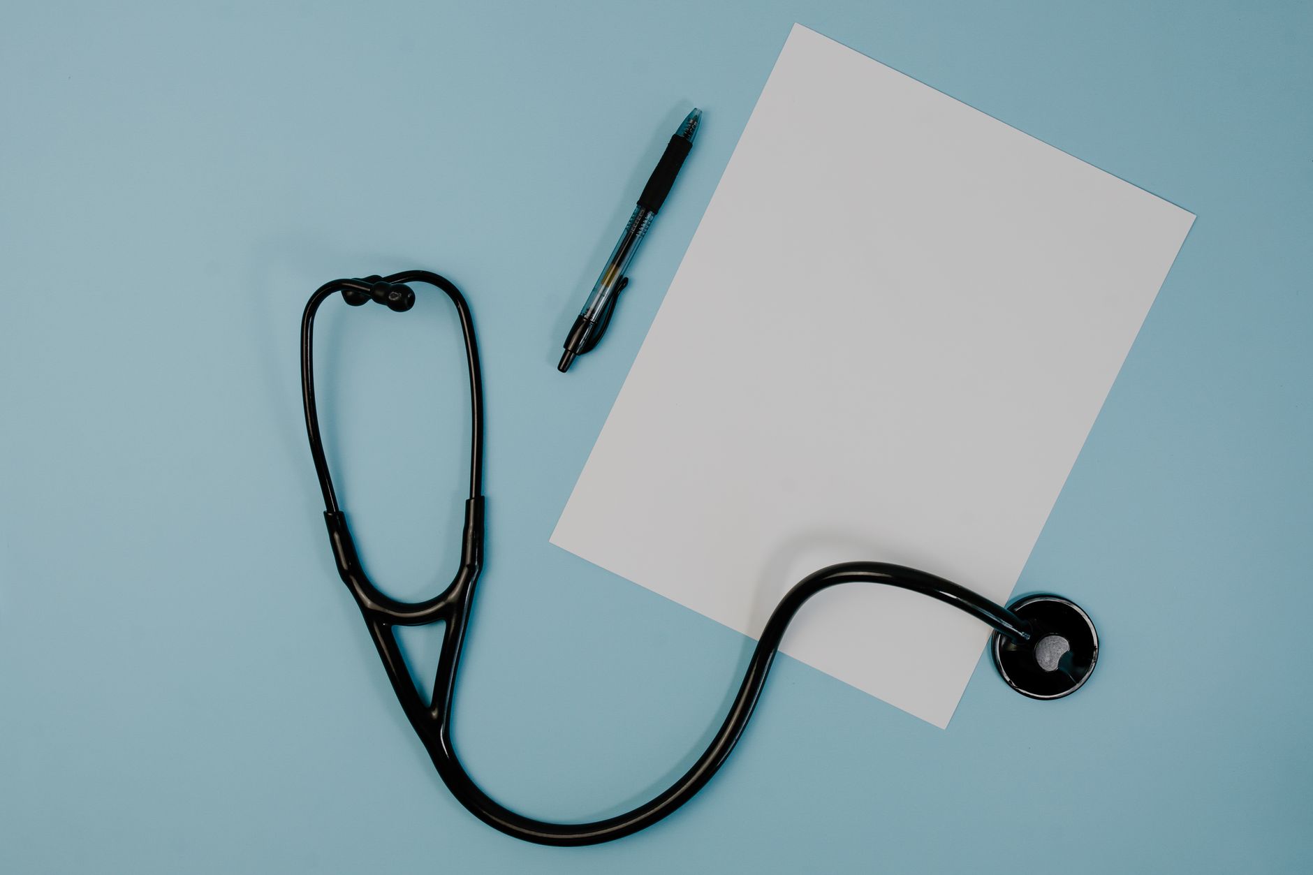 Flat lay of stethoscope, blank paper, and pen on blue surface — CBD Gummies: What Makes Them So Good And So Popular?