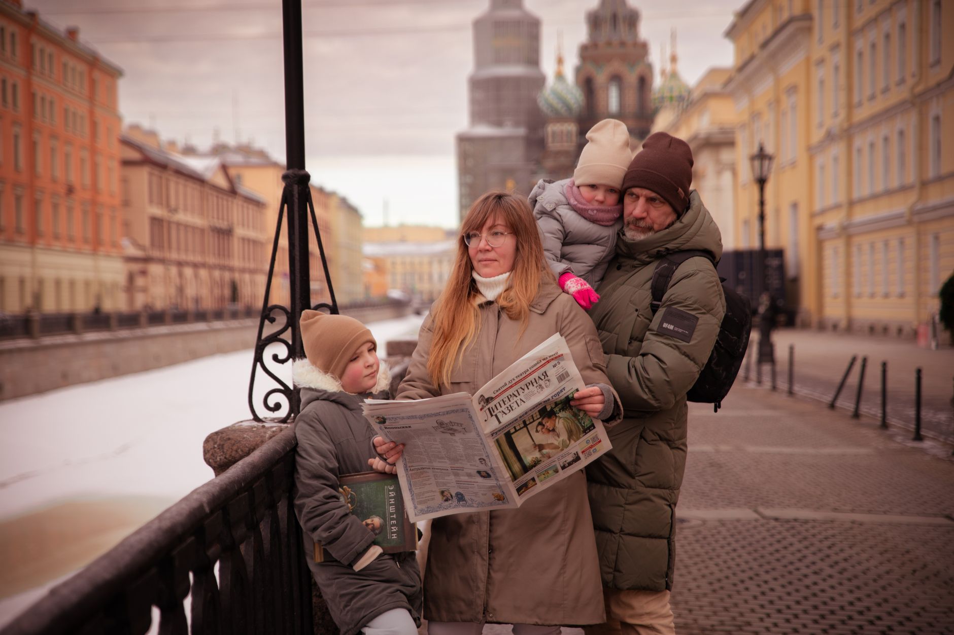 A family strolls along a canal in Saint Petersburg on a winter day, bundled up warmly against the cold. — Commercial Tent Sal