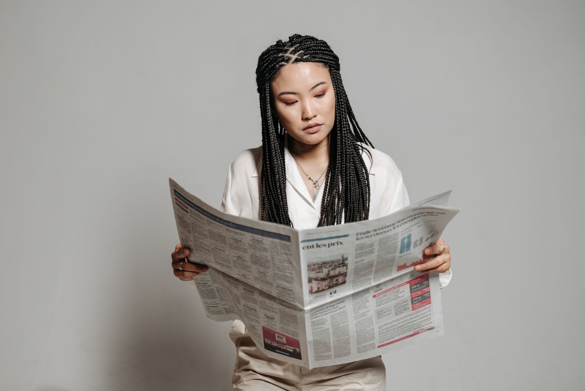 Woman with braided hairstyle reading a newspaper indoors, showing leisure and focus. — Consuming Quality Fat Burners and Abou