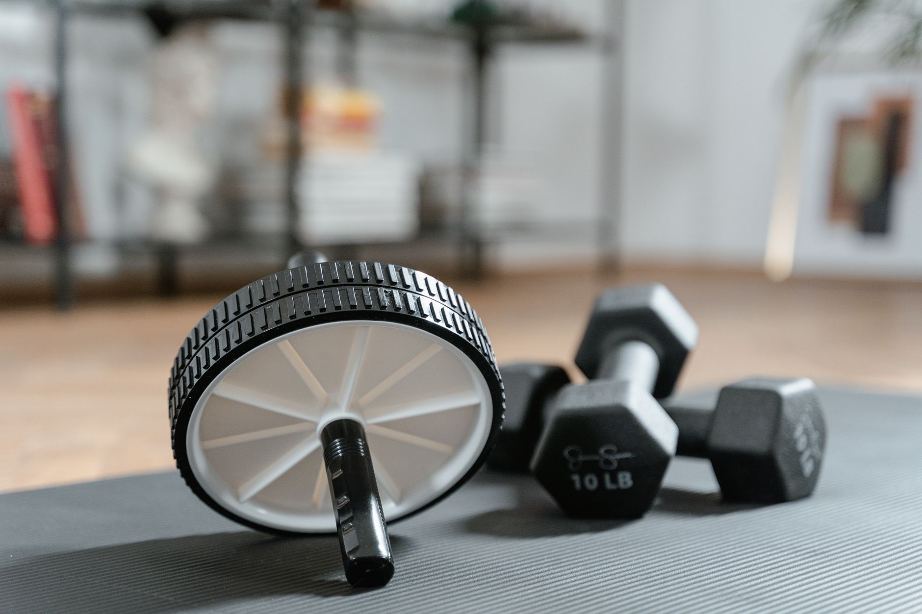 Ab roller and dumbbells on yoga mat, perfect for a home workout routine and healthy lifestyle. — Exercise Equipment Maintenan