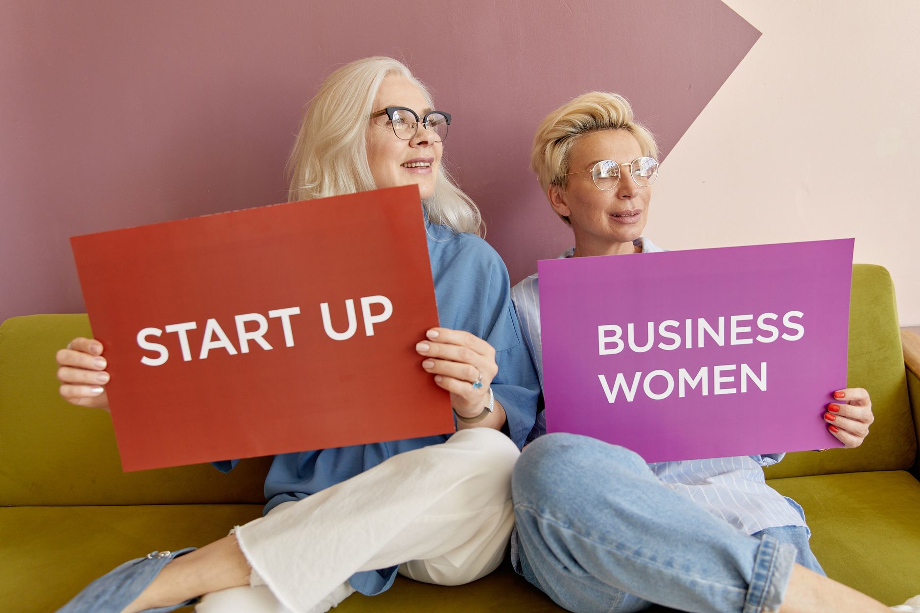 Two women on a sofa holding signs promoting startup and business women. — Explore the Rise of Tasty Health Supplements