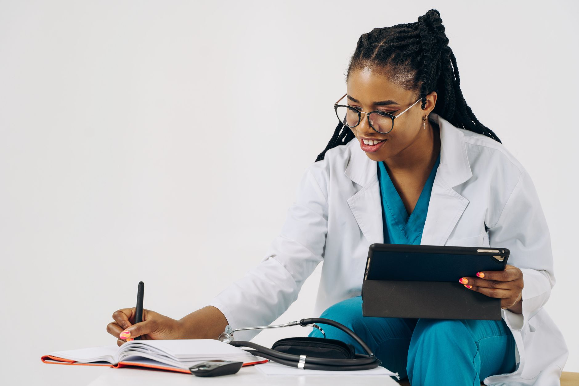 Smiling female doctor in scrubs using tablet and taking notes in a healthcare setting. — Exploring the Anti-inflammatory Effe