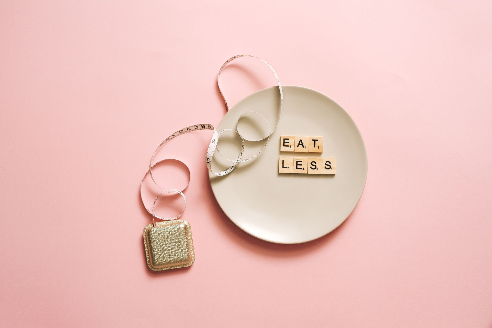 A motivational image featuring a plate with scrabble tiles spelling 'Eat Less' on a pink background. — Extreme Diets For Rapi