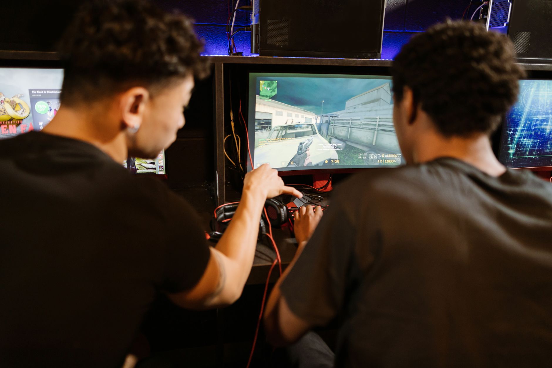 Two young men playing a multiplayer computer game at an arcade with enthusiasm and focus. — Feel the Rush with Live Dealer Ga