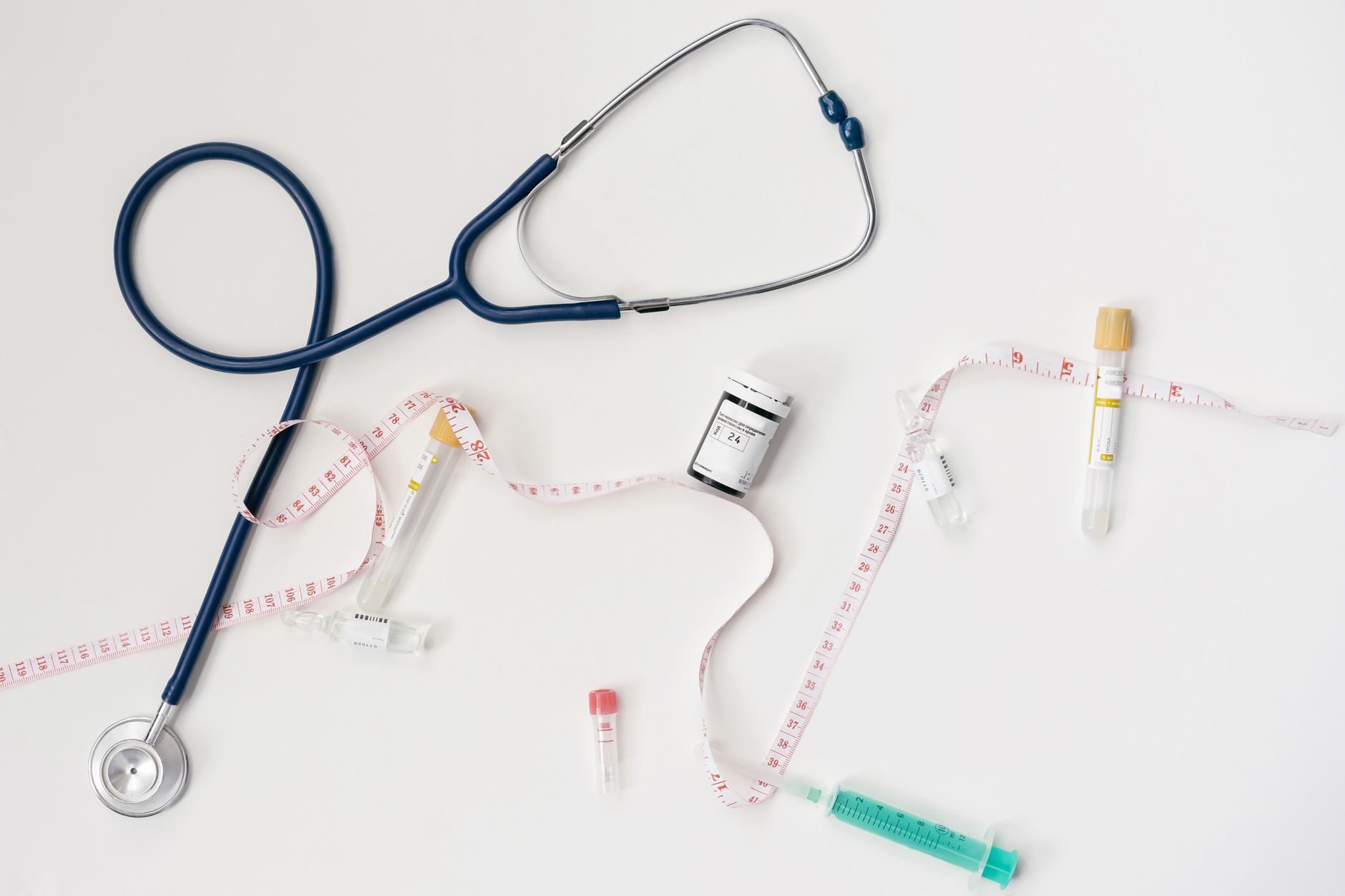 Top view of stethoscope, syringes, and tape measure on white background. — Filing a drug-related lawsuit: You need an experie