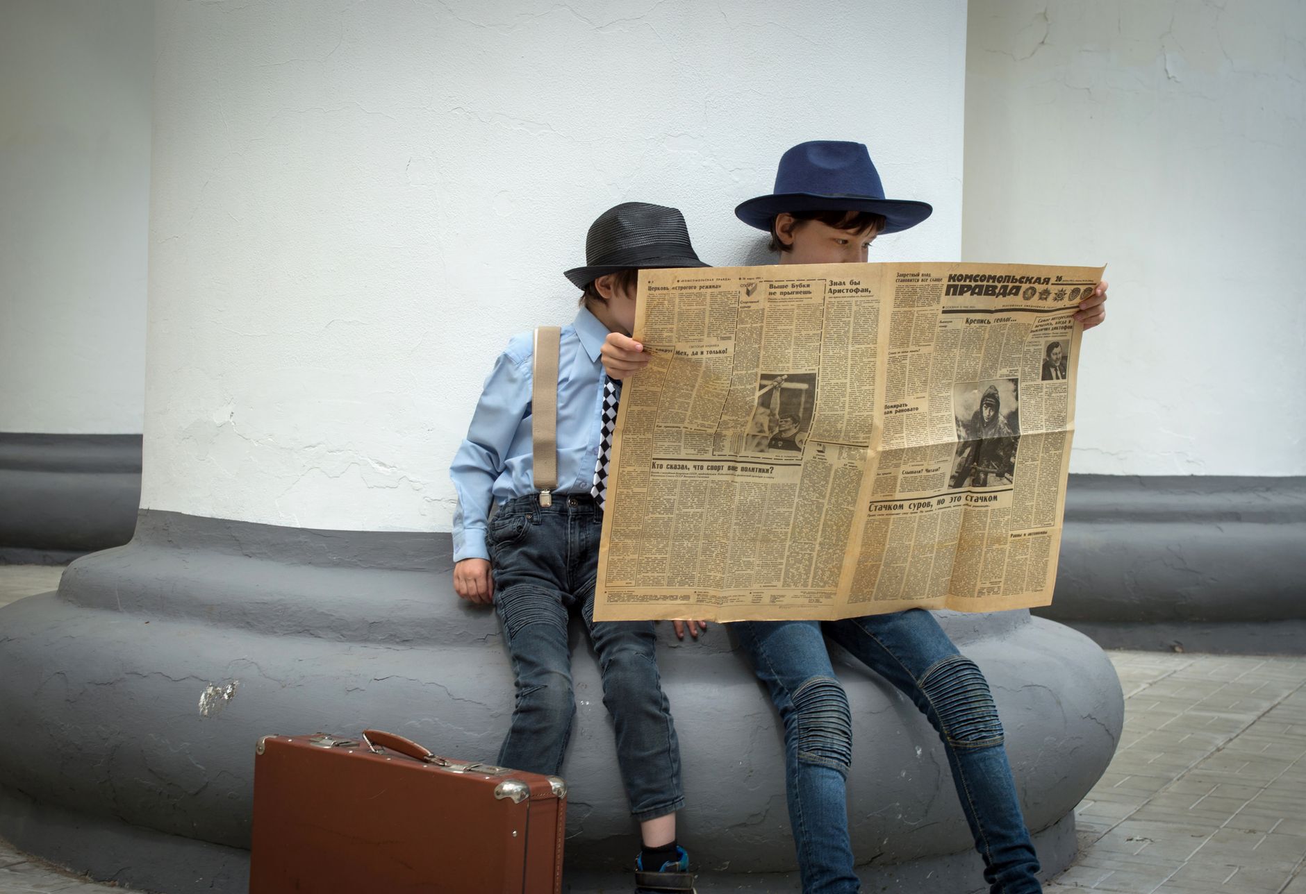 Two stylish children in hats reading a vintage newspaper outdoors. — Green Hut's Volcano Vaporizer: Where Quality and Innovat