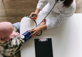 A medical practitioner checks a patient's blood pressure in a clinical setting, showcasing healthcare service. — Health insur