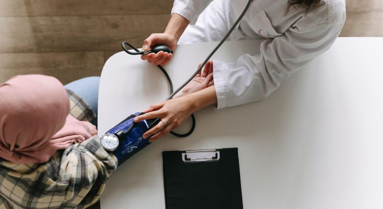 A medical practitioner checks a patient's blood pressure in a clinical setting, showcasing healthcare service. — Health insur