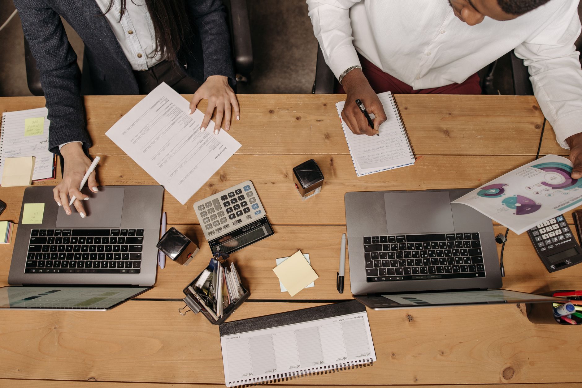 High-angle view of professionals working collaboratively with laptops and documents in an office. — Increase Visibility With