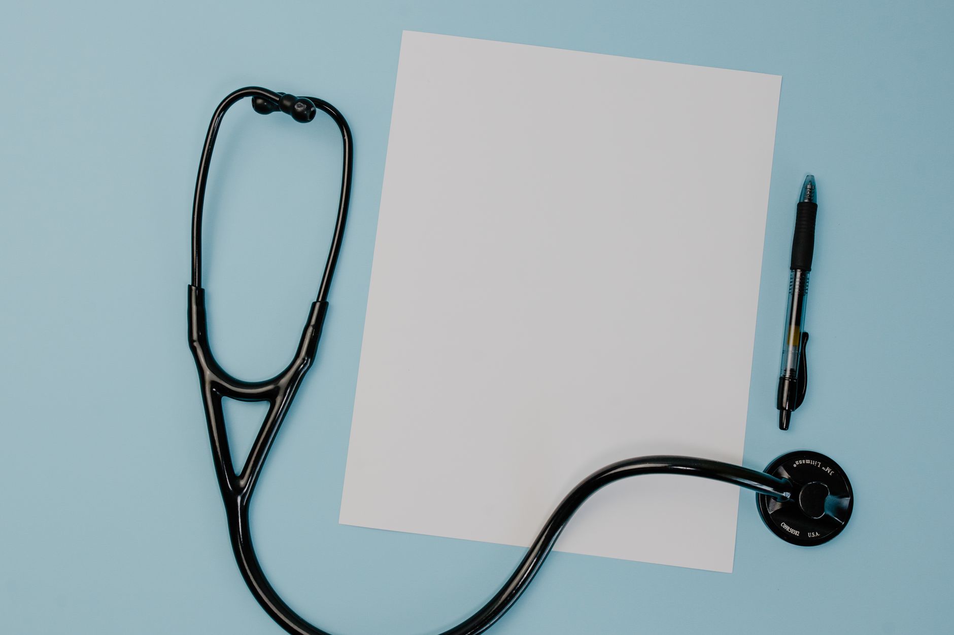 Flat lay of a stethoscope, blank paper, and pen on a blue background. — Legally Buying Adipex Online