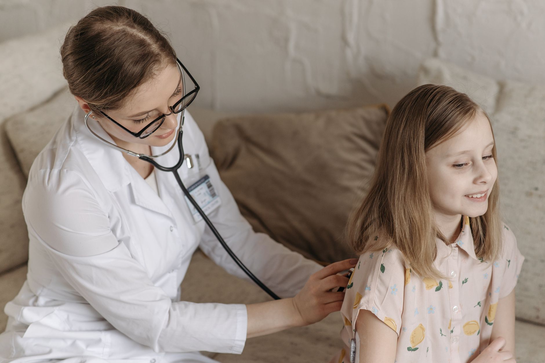 A doctor with a stethoscope examining a smiling girl during a medical check-up at home. — Physiotherapy for Knee Pain: A Comp