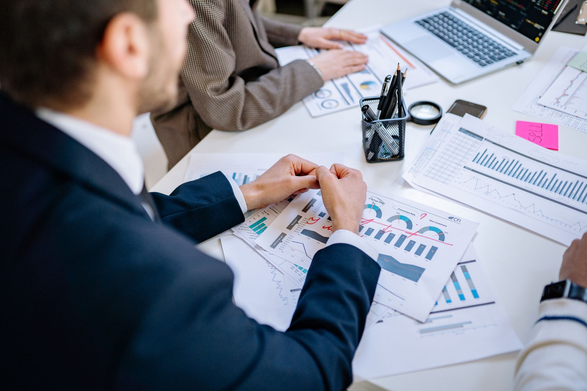 Business team analyzing financial graphs at a meeting table, fostering collaboration in an office environment. — Radiant Comp