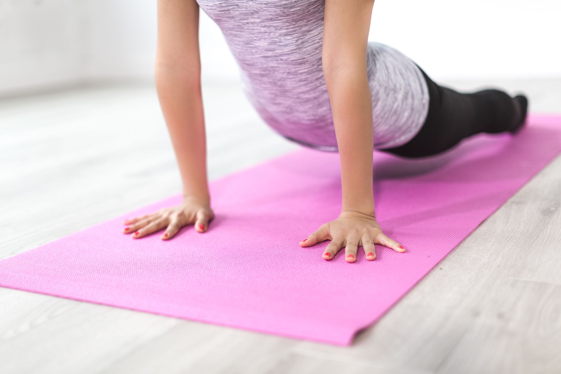 A woman performs a yoga stretch indoors on a pink mat, promoting a healthy lifestyle. — Reside In Fit Camp - Evolution of Fit