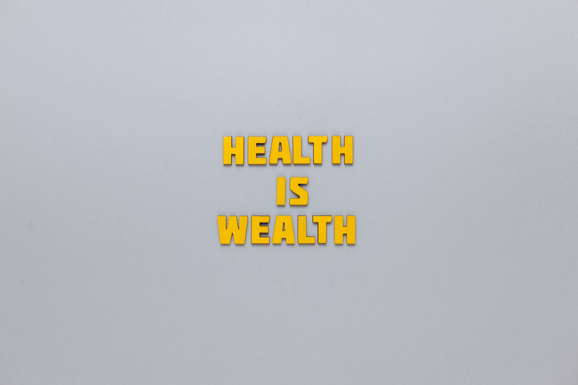 Inspirational phrase 'Health is Wealth' in bold yellow letters on a neutral gray background. — StreamEast NFL Subscription Pl