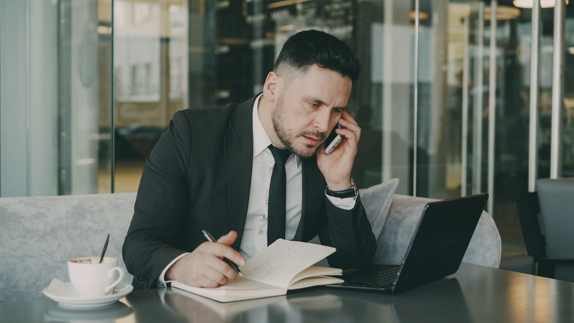 Businessman talks on phone while writing notes in a modern cafe. — THC Syrup Adds Potency to Your Favorite Beverages