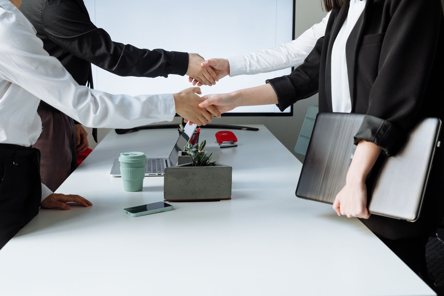 Professionals sealing a deal with a handshake across a conference table during a business meeting. — THCA Weed: An Underexplo