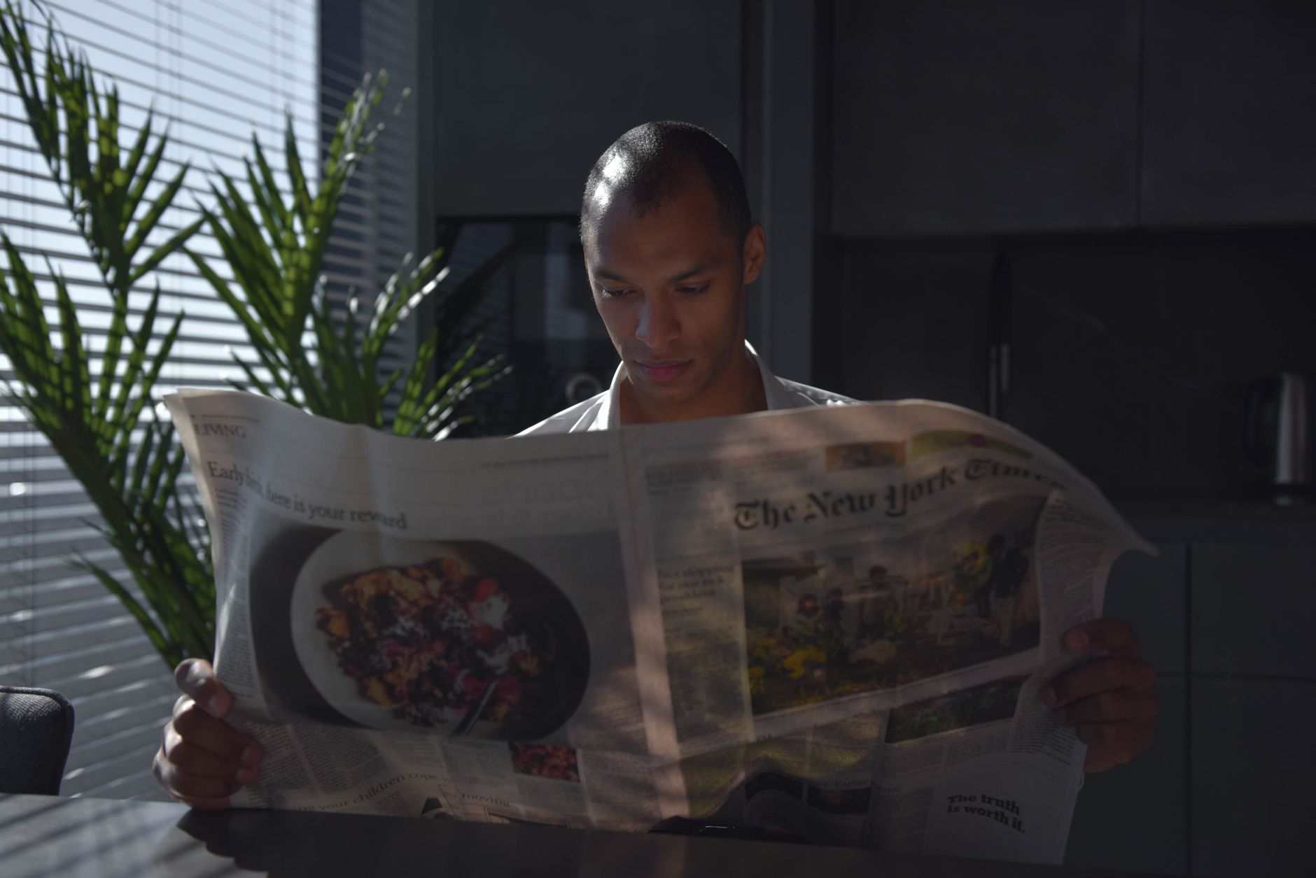 Businessman focused on reading newspaper in a sunny indoor office setting. — The Greenmates: Why Are They The Best Edible Del