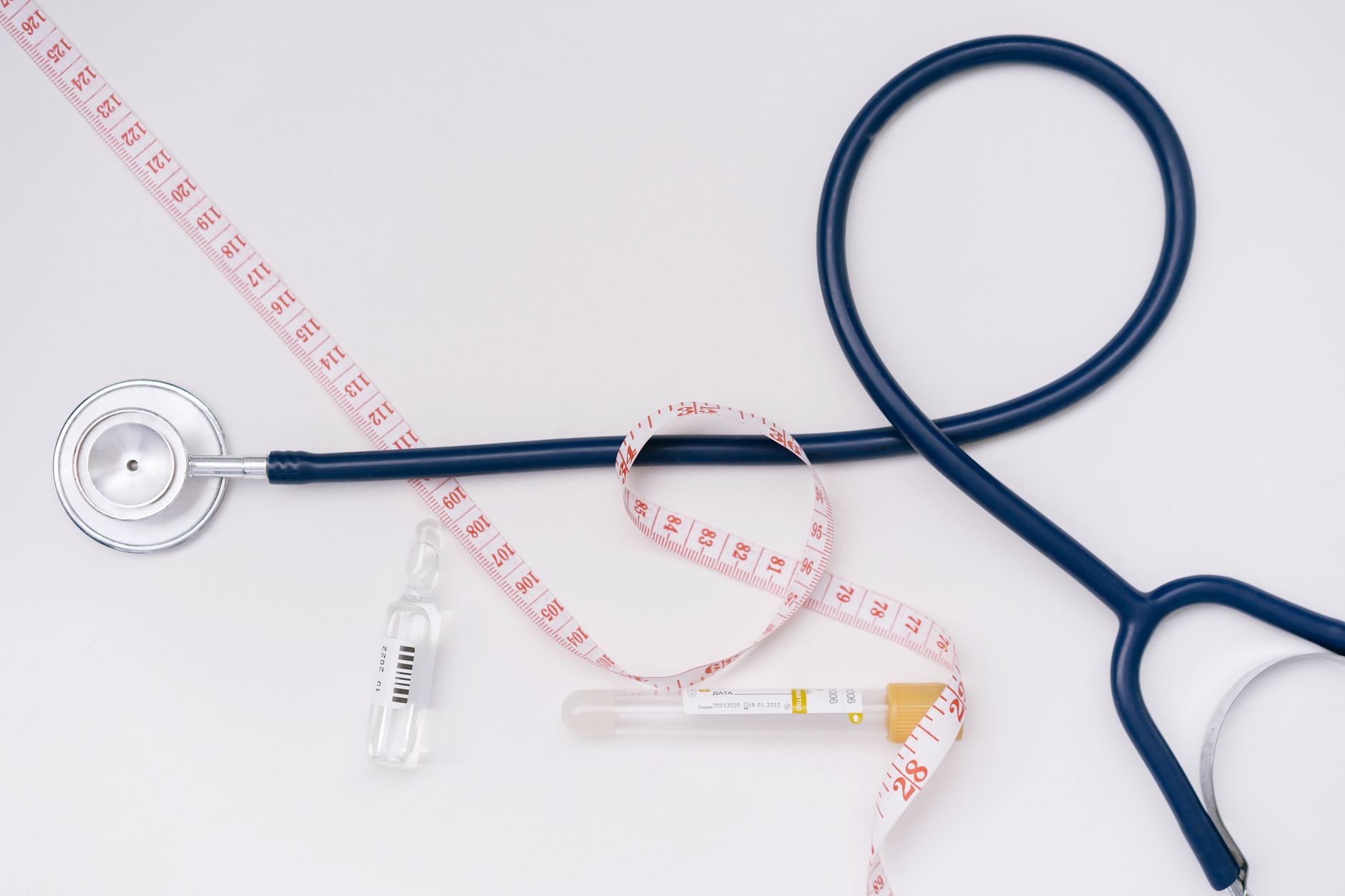 A stethoscope, ampoule, and tape measure on a white background symbolize healthcare essentials. — The Importance of Self-Assu