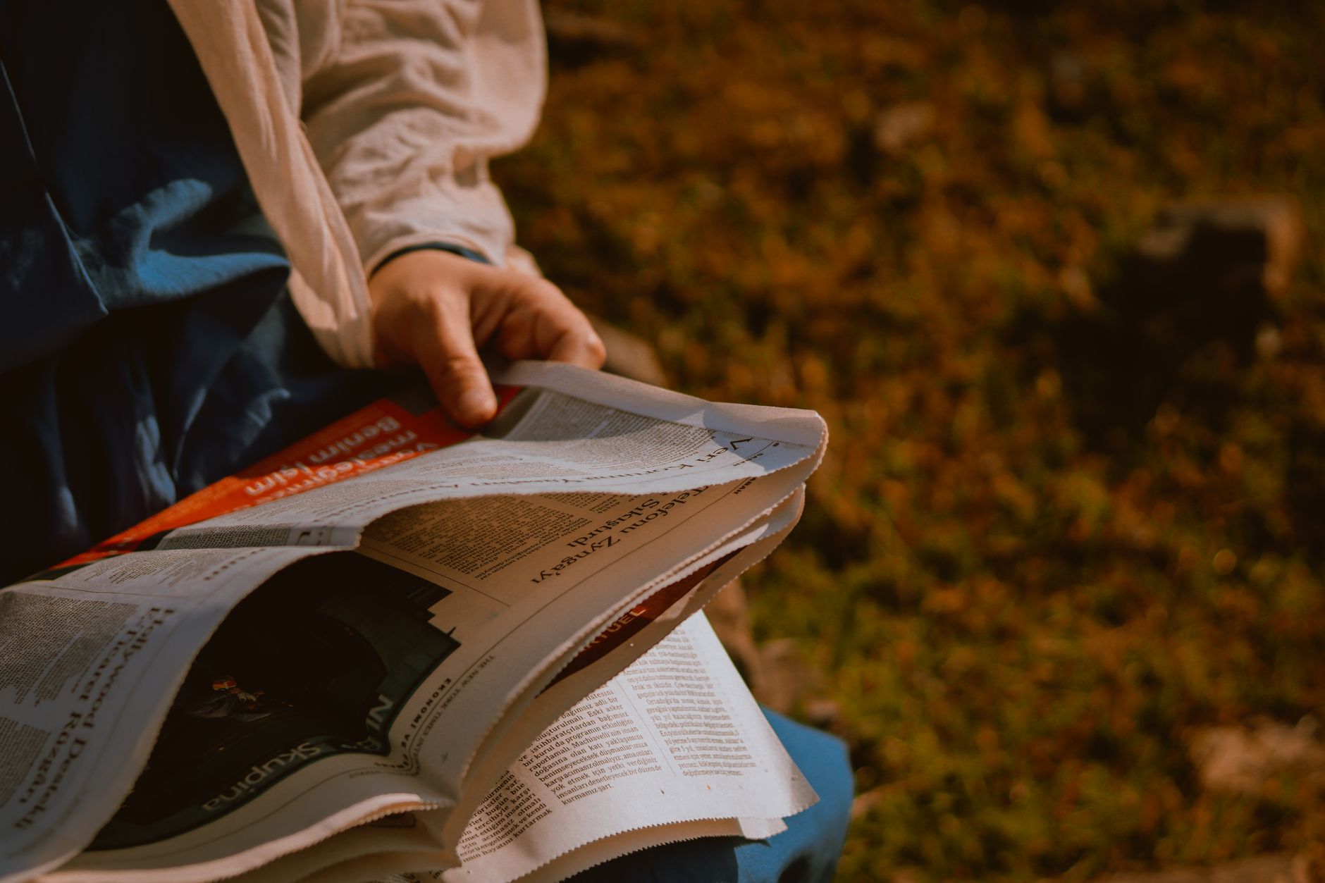 From above of crop unrecognizable person reading newspaper on green meadow in daylight — Things to consider while purchasing