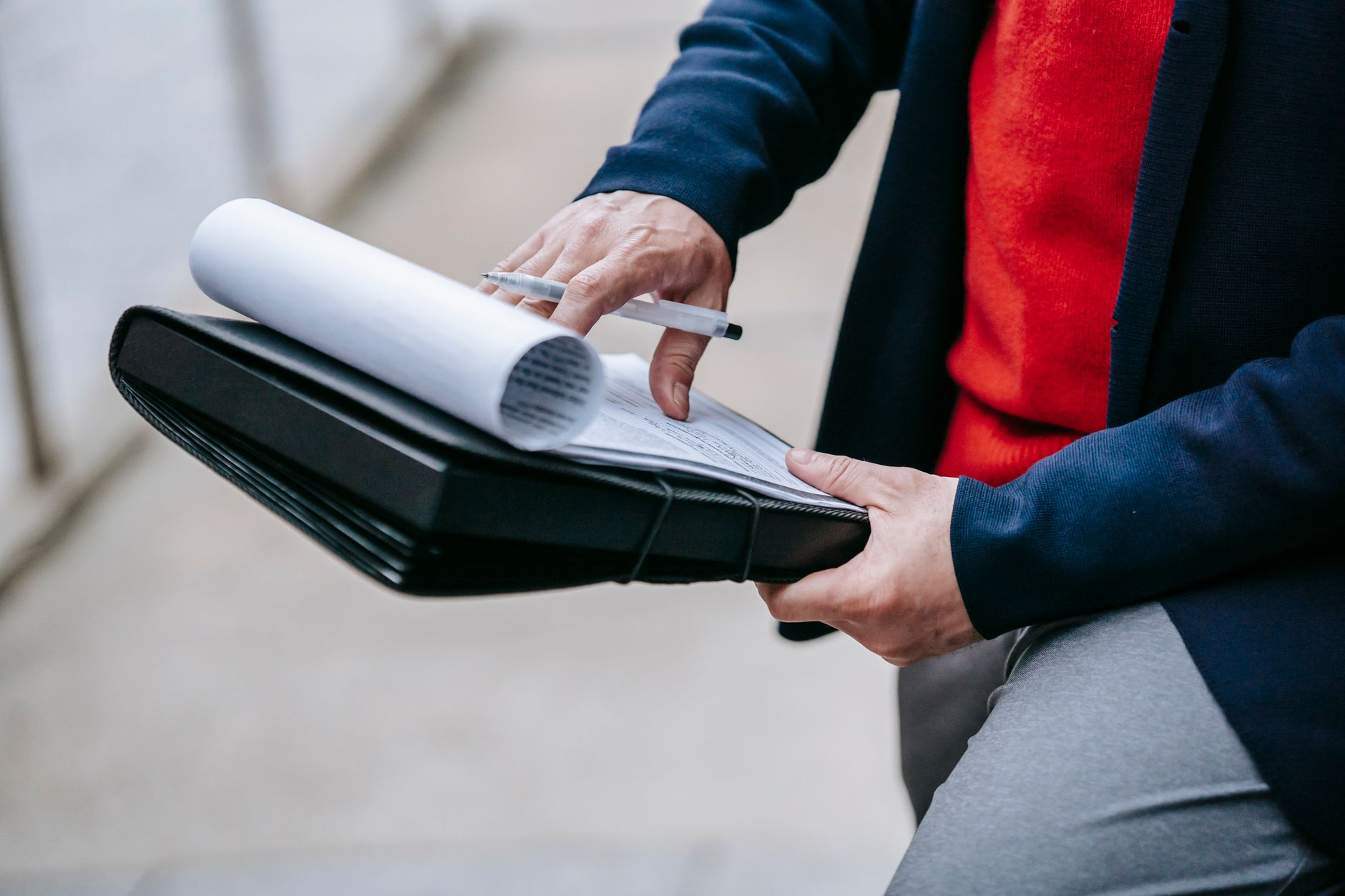 Close-up of a professional person reviewing documents outdoors. Engaged in work with focus on writing materials. — Viking IPT