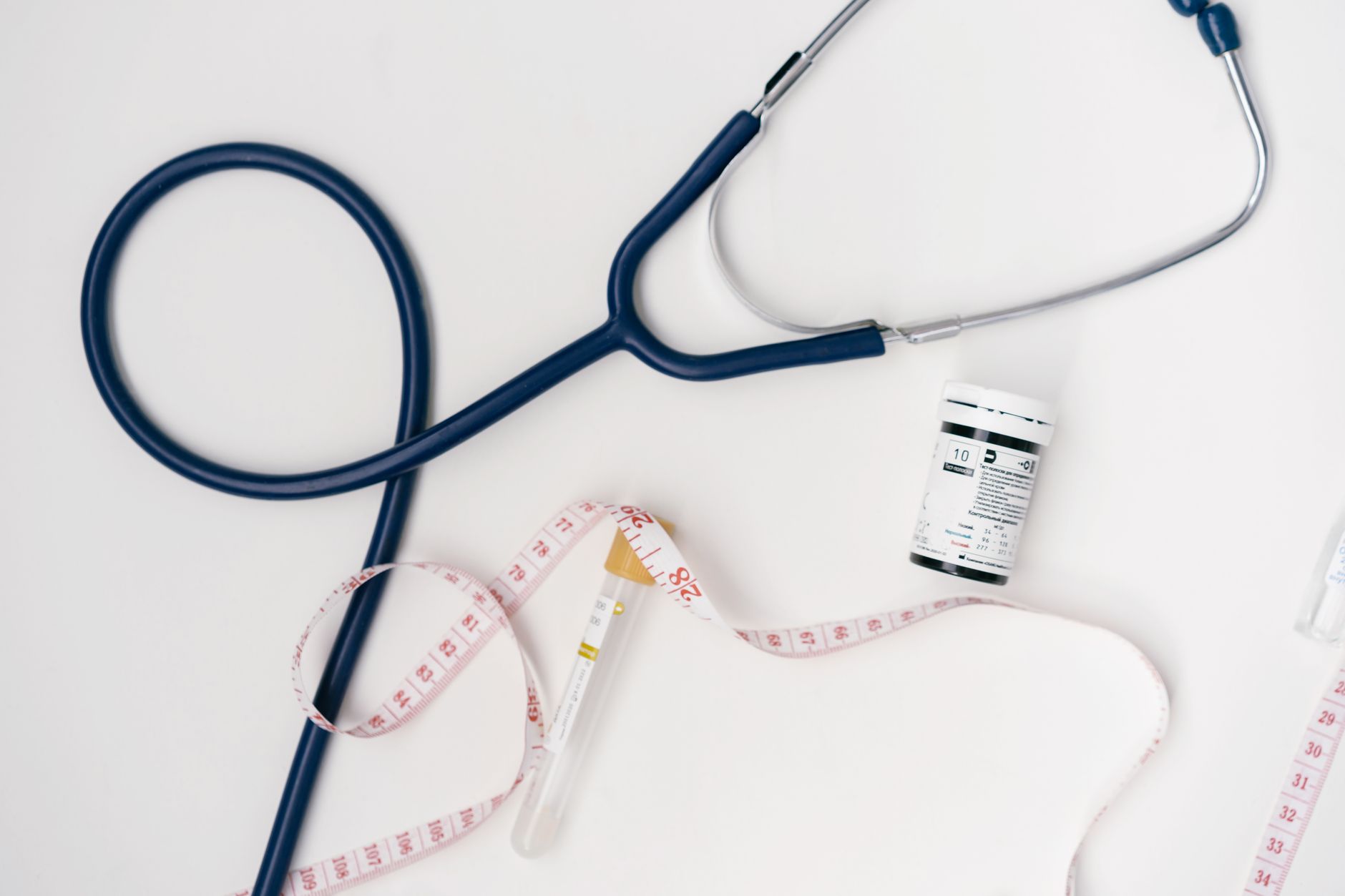 Flat lay of medical tools including stethoscope and measuring tape on a white background. — What Are the Types of Weight Loss