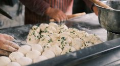 Close-up of hands shaping fresh dough balls with herbs at a bakery counter. — What's Within The Food You're Eating, And Which