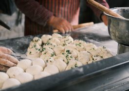 Close-up of hands shaping fresh dough balls with herbs at a bakery counter. — What's Within The Food You're Eating, And Which