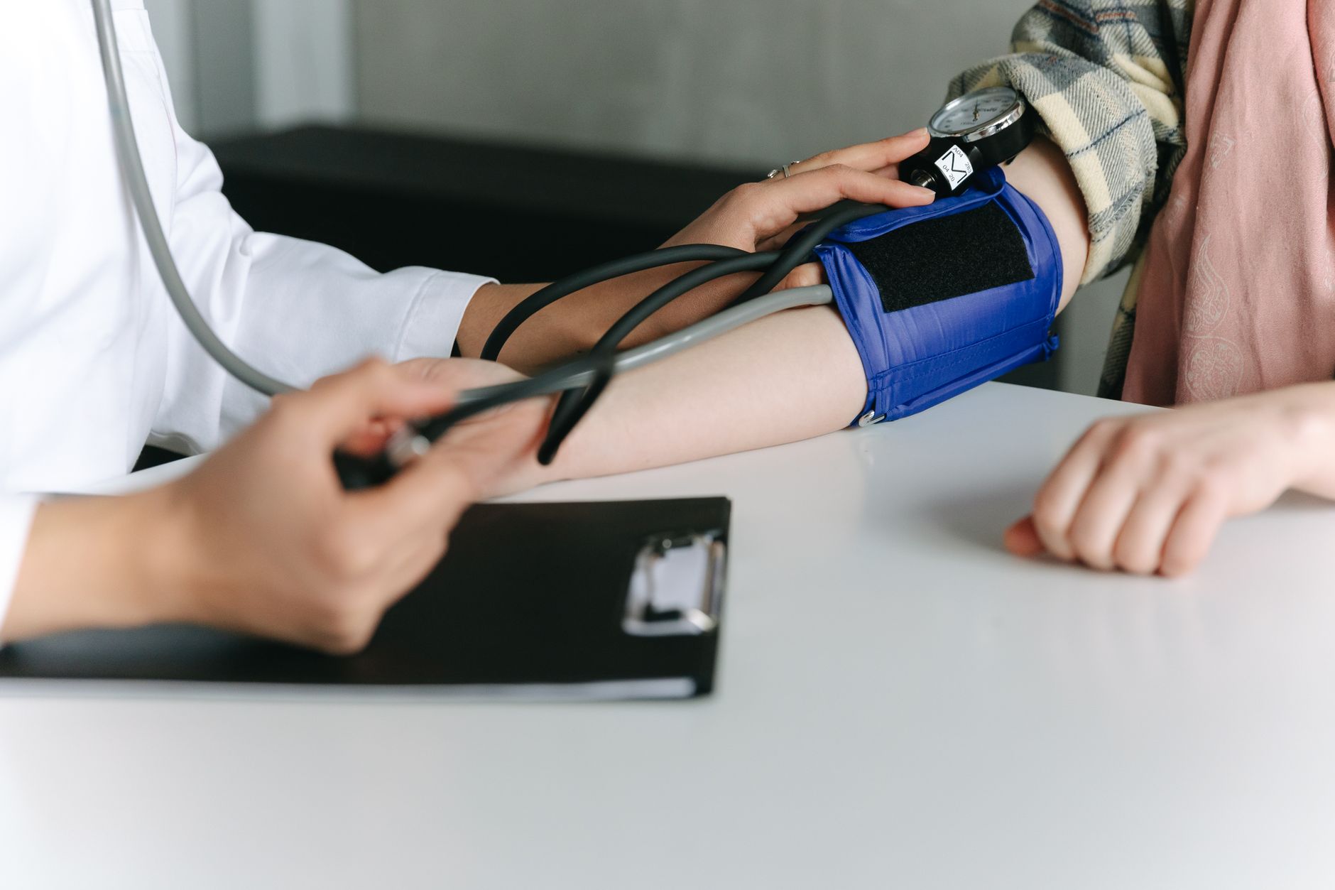 A healthcare worker uses a sphygmomanometer to check a patient's blood pressure in a medical office. — Wholesale Drug Tests –