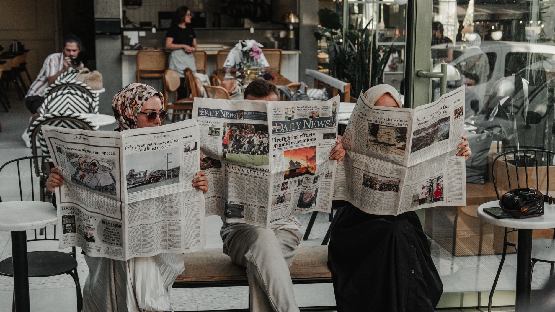 Three adults reading newspapers in a modern Ankara café, enjoying leisure time. — Why Choose Enlight Treatment Center?