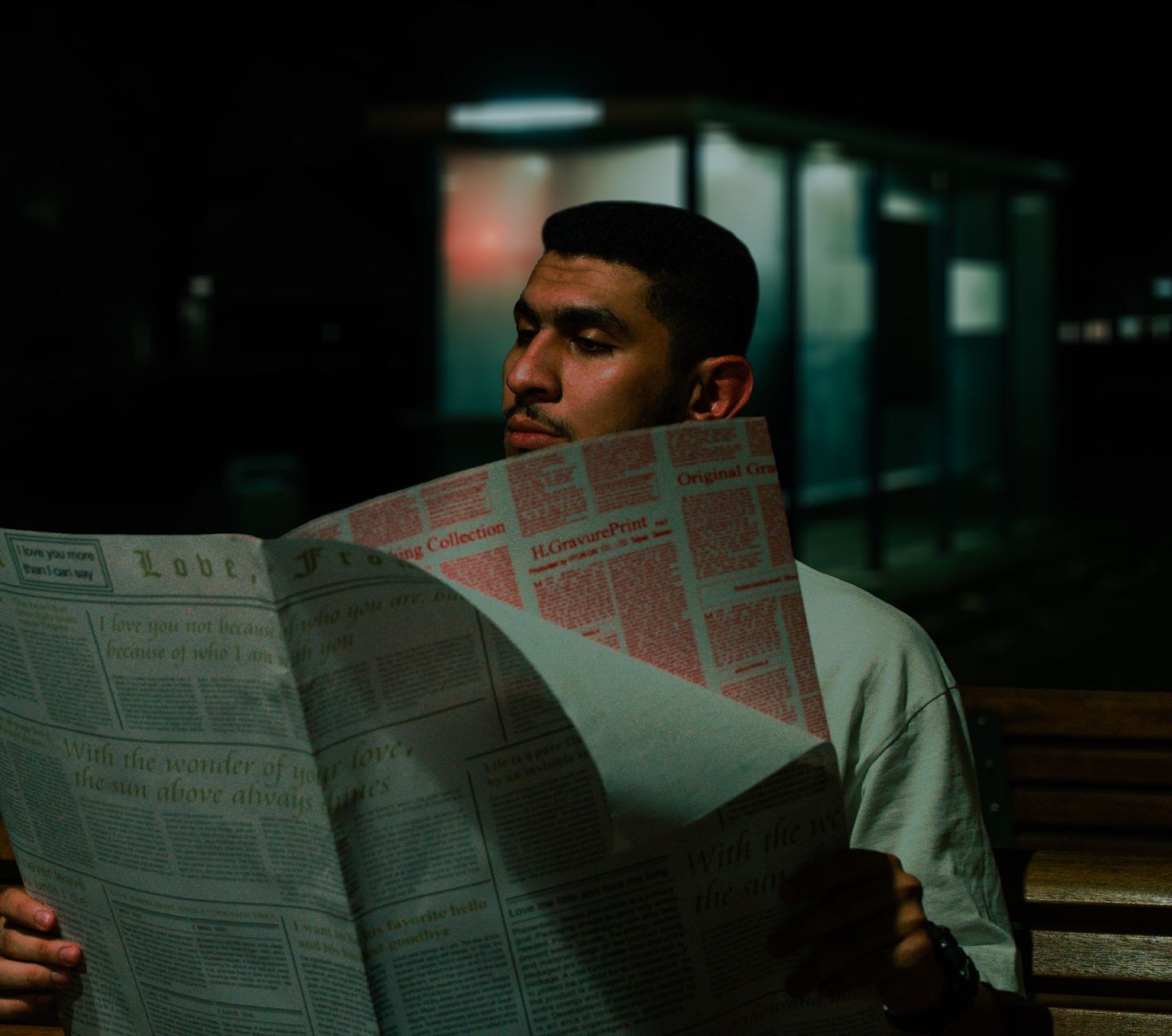 A man reads a newspaper at night on a bench, surrounded by urban darkness. — Why Should Students Prefer Getting Their Resume