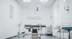 a clean and well-lit medical examination room with an operating table and surgical equipment