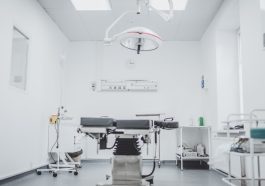 a clean and well-lit medical examination room with an operating table and surgical equipment