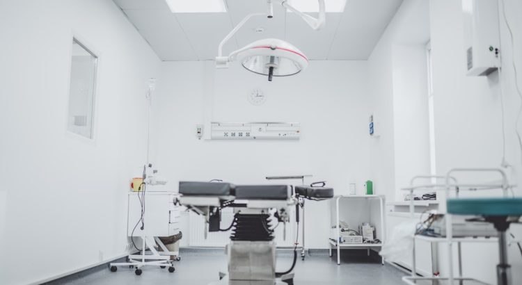 a clean and well-lit medical examination room with an operating table and surgical equipment
