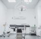 a clean and well-lit medical examination room with an operating table and surgical equipment
